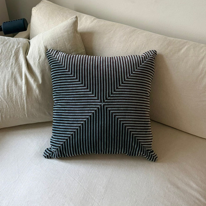 Striped pillow on a beige sofa with a neutral background