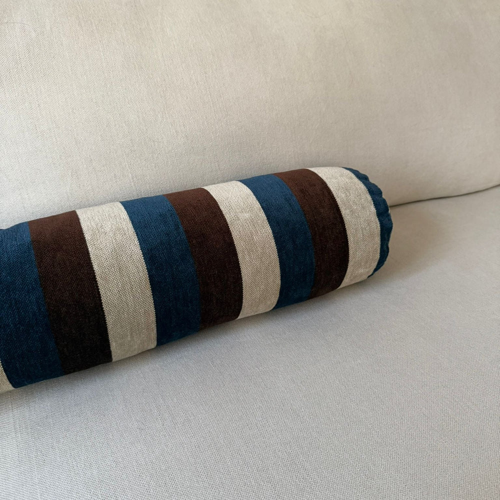 Striped cylindrical pillow on a beige sofa