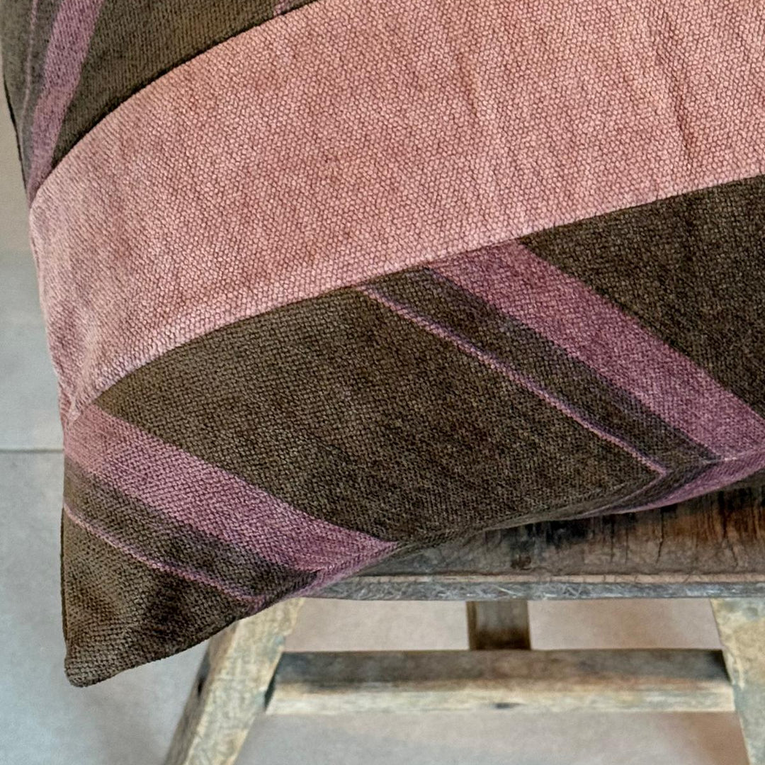 Textured fabric with pink and brown stripes draped over a wooden stool.