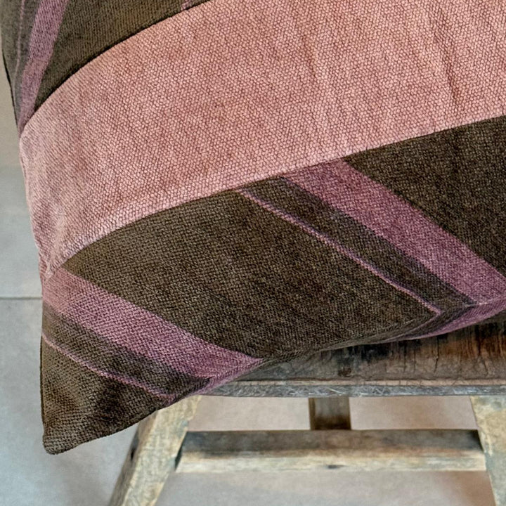 Textured fabric with pink and brown stripes draped over a wooden stool.